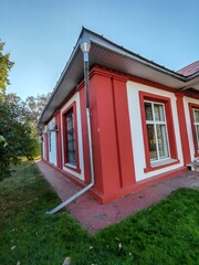 white building with a large window framed in red, featuring a neat reflection of the surroundings. The architecture captures the balance between clean, simple design and bold, colorful elements.