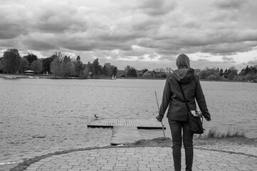 Dziewczyna stojąca na brzegu jeziora patrząca w zachmurzone niebo, czarno-biała fotografia  © Paweł Kacperek