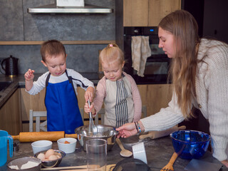 Mother and her children bond while making cookie dough together in a contemporary kitchen, learning new skills and creating lasting memories, concept of cooking food from dough, cook at home
