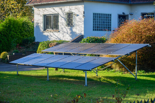 Solar panels, mounted on the ground in the yard of a residential home, efficiently capture sunlight to generate renewable energy.