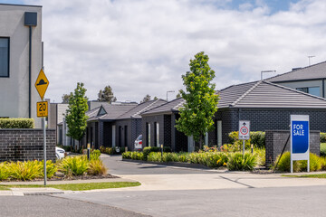 Contemporary Residential Complex: Row of Townhouses. Modern Australian Suburban Street: New Housing Development and For Sale Sign. New Housing Estate: Townhomes with Street Landscaping in a suburb.