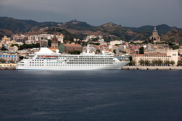 View of the city of Messina in Sicily from the strait. A cruise liner in front of it.
