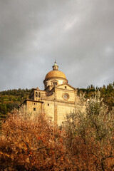 View of the church of Santa Maria Nuova, Cortona. Looking up through bushes and trees.