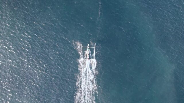 Descending aerial drone shot in Indonesia, Bali, fishing boat returns from fishing in the morning, Amed, Karangasem, Bali, Indonesia.