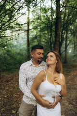 Fototapeta premium A man hugs a woman outdoors in the forest