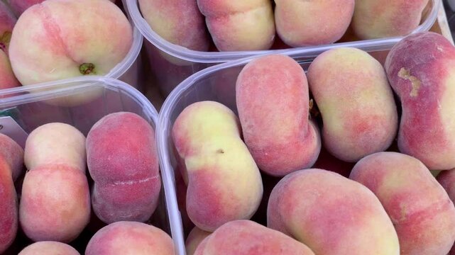 A display of sweet Saturn peaches at a lively market in Southern Italy. These unique, flat peaches are a beloved summer treat, celebrated for their exceptional flavor and juiciness.