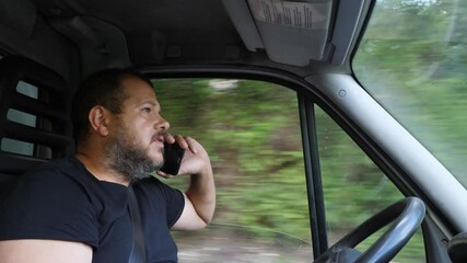 A truck driver dangerously talks on the phone while driving, highlighting risky behavior and lack of attention to the road, posing a threat to road safety.