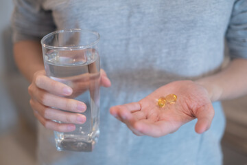 Hand holding fish oil vitamin supplement pill tablet capsule healthy lifestyle high omega 3 nutritional supplement illness prevention, drinking water in hand fish supplement healthcare and medicine