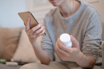 Adults holding vitamin medicine using smartphone mobile phone searching reading looking drug...