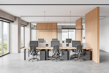 Modern coworking interior with desks and pc monitors, panoramic window