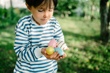 Boy carrying colorful easter eggs in park