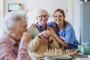 Happy healthcare worker with senior man and woman drinking tea at home