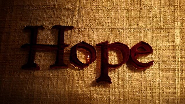 A single candle illuminates the word hope