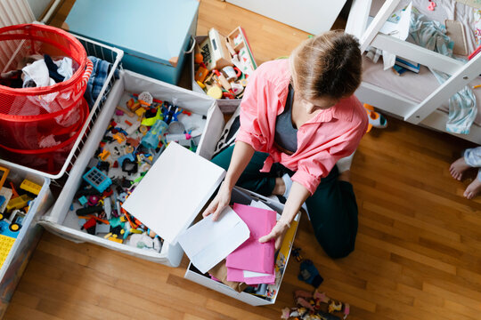 Woman organizing papers and toys in bedroom at home