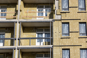 Installation of windows in an apartment building under construction, insulation of walls with insulating materials