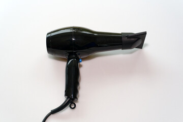 Top view of black hairdryer with cable against white background. Photo taken October 28th, 2024, Zurich, Switzerland.