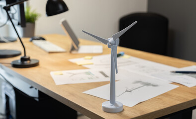 Wind turbine standing on office desk with project papers