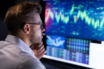 Stock market analyst working in front of computer screen