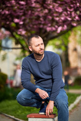Obraz premium Man allergic enjoying after treatment from seasonal allergy at spring. Portrait of bearded man in front of blossom tree at springtime. Spring allergy concept.