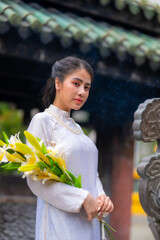 Vietnamese girl with Ao Dai dress standing in temple in Ho Chi Minh city, Vietnam. Ao dai is famous traditional costume for woman in Vietnam