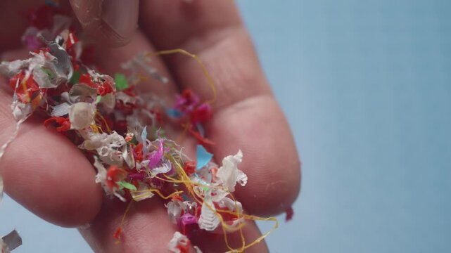 In slow motion, microplastic particles trickle from fingers, vividly portraying environmental pollution and sample testing.