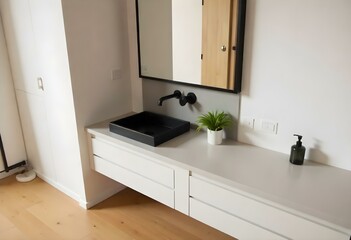 A modern bathroom with a large mirror, a minimalist sink, and a potted plant.