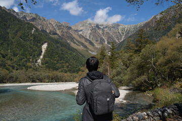 Young male tourist traveling to Kamikochi, Nagano in Japan. Solo backpacker looking at alps mountain views