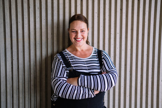Smiling woman with arms crossed in front of textured wall