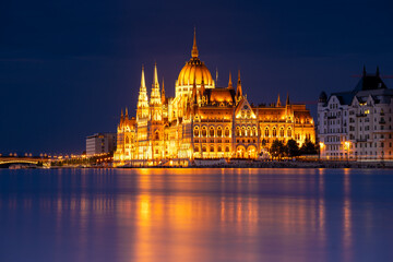 Obraz premium Budapest, Hungary - September 17, 2024: Budapest Parliament Reflecting Over Danube in the Night. Night long exposure shot.