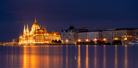 Obraz premium Budapest, Hungary - September 17, 2024: Budapest Parliament Reflecting Over Danube in the Night. Night long exposure shot.