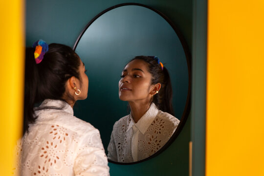 Smiling woman with ponytail looking in mirror