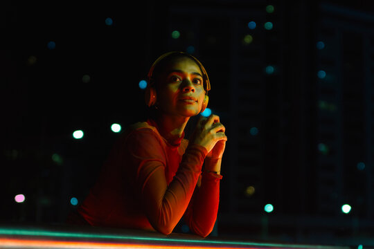 Woman listening music on headphones and contemplating at night - Powered by Adobe