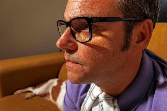 Mature man wearing eyeglasses and watching TV on sofa at home