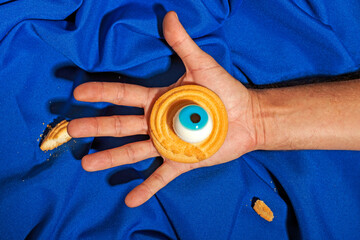 Hand showing Halloween cookie with scary candy eye