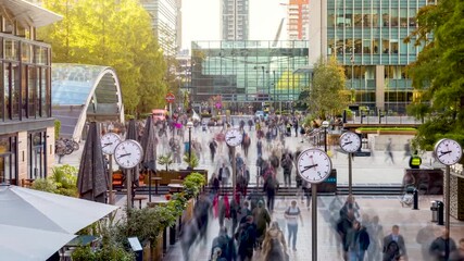 Sunrise timelapse view of motion blurred business people rushing to work in the moring at the financial centre Canary Wharf, London - Powered by Adobe