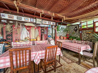 Cozy, rustic restaurant with a fishing at Lake Ohrid in North Macedonia. Walls are adorned with fishing nets, old photos, and other nautical decorations. Summer travel destination in the Balkans
