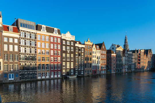 Dancing houses at Damrak and tower of Oude Kerk Amsterdam Church at sunset, Amsterdam, The Netherlands, Europe