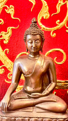 Golden bronze Buddha statue in meditation pose with gentle serene smile exuding warmth and...