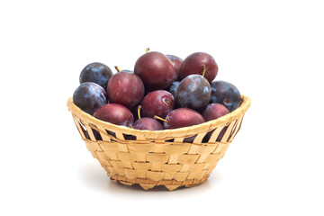 Basket of ripe plums isolated on white background.