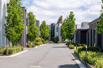 The street is clean and contemporary, lined with new residential townhouses or modern homes...