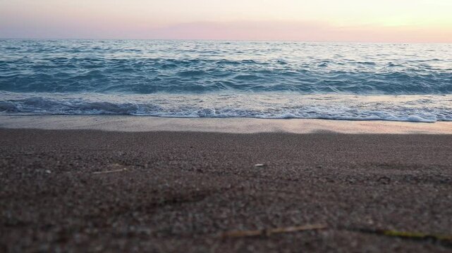 Waves gently lap at shore during stunning sunset over ocean. Golden sunlight reflects off waves as they roll onto shore, creating tranquil atmosphere at sunset by sea. Montenegro summer, Canj