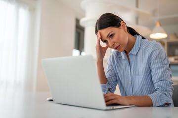 Stressed business woman with headache working from home on laptop looking tired and overwhelmed