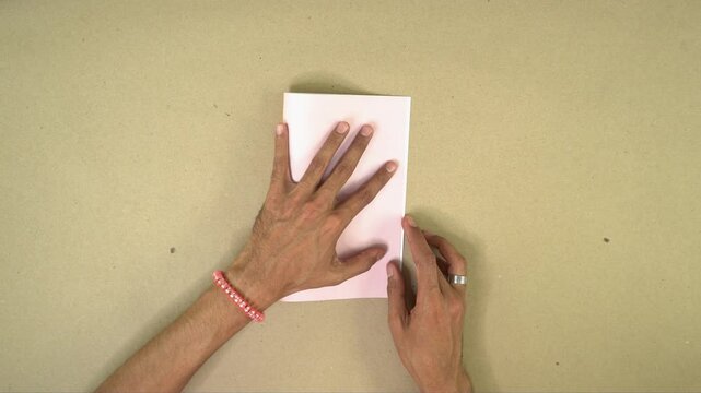 Hands folding sheet of decorated cardboard