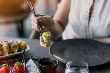 Elegant dining scene featuring chopsticks picking up sushi roll