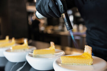 Chef using culinary torch to caramelize lemon tart slices