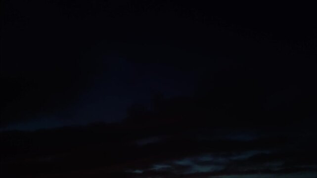 Night landscape with moving cirrus clouds with reddish tints