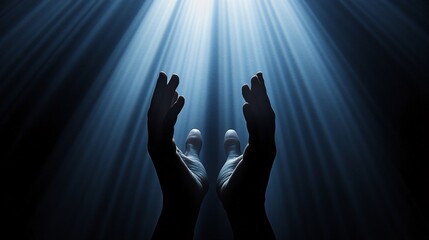 Praying hands in the dark with rays of light coming from above.