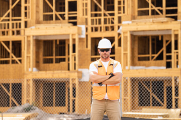 roofer builder working on roog structure of building on construction site. handsome young male builder in hard hat smiling at camera. Construction Worker on Duty. Contractor and the Wooden House Frame