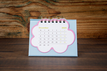 December 2025. Cardboard desk calendar on a wooden texture background