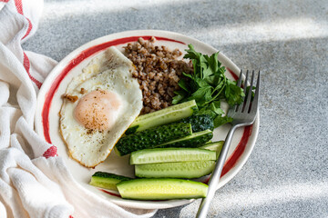 Close-up overhead view of a breakfast plate with Fried egg, buckwheat, cucumber and parsley
